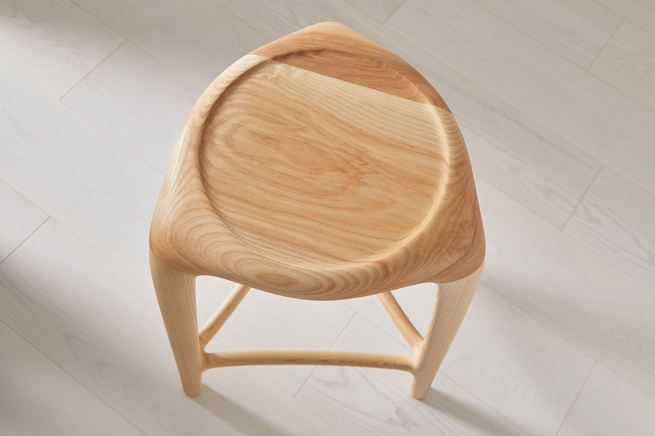 Close-up of circular recessed seat on tripod ash stool from a high angle