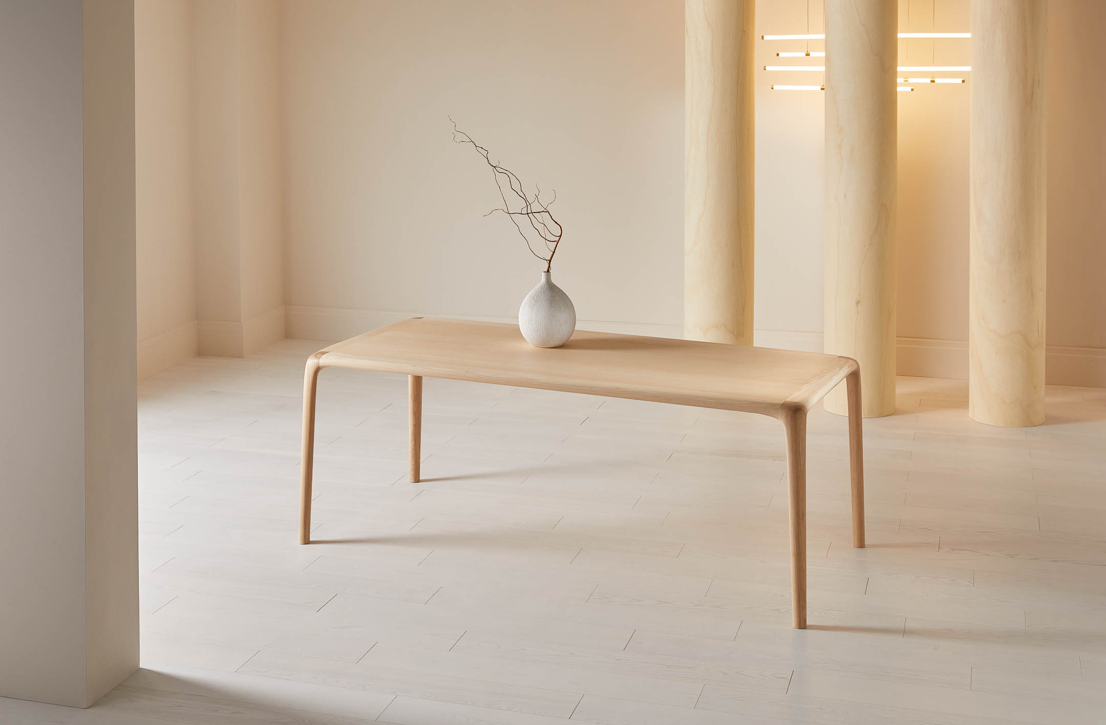 Minimalist ash wood dining table with a vase on top. photographed in a warm neutral interior